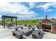 Backyard patio featuring a pergola, fire pit, outdoor kitchen, and green views at 20503 E 50Th Pl, Denver, CO 80249