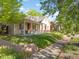 Quaint home with inviting front porch, complemented by lush greenery and a charming brick wall at 3929 Shoshone St, Denver, CO 80211
