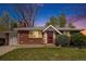 Charming brick home with a well-manicured lawn, complemented by mature trees and a colorful sunset at 8209 Benton Way, Arvada, CO 80003