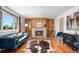 Comfortable living room with a stone fireplace, hardwood floors, blue velvet sofa, and lots of natural light at 8209 Benton Way, Arvada, CO 80003