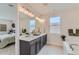 Bright main bathroom with double vanity, modern lighting, and a glimpse into the adjacent main bedroom at 12762 Bend Ct, Firestone, CO 80504