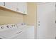 A laundry room with front loading machines and white cabinets above at 708 S Carlton St, Castle Rock, CO 80104