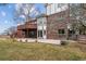 Back exterior showing a brick facade, wooden deck with lattice, a manicured lawn, and mature trees at 9117 Buck Hill Dr, Highlands Ranch, CO 80126