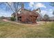 Expansive backyard featuring a spacious deck, mature trees, lush grass, and brick-paved pathway at 9117 Buck Hill Dr, Highlands Ranch, CO 80126