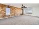 Spacious living room featuring exposed brick wall, neutral carpet and a ceiling fan at 5131 Netherland St, Denver, CO 80249
