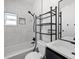 Updated bathroom featuring white marble tile, shower and tub combo, and black fixtures at 4232 S Grant St, Englewood, CO 80113