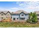 Two-story blue home with a fenced yard, patio, and sliding doors with green grass in the foreground at 15602 E 117Th Ave, Commerce City, CO 80022