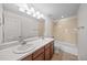 Bright bathroom with dual sinks, ample lighting, wood cabinets and shower-tub combo at 15602 E 117Th Ave, Commerce City, CO 80022