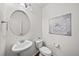 Well-lit powder bathroom boasts a pedestal sink, round mirror and decorative flower wall art at 15602 E 117Th Ave, Commerce City, CO 80022