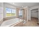 Beautiful bathroom featuring a soaking tub, glass-enclosed shower, and a scenic window view at 15602 E 117Th Ave, Commerce City, CO 80022