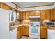 Functional kitchen with tile countertops, ample wood cabinets, and white appliances at 1542 Kilkenny, Boulder, CO 80303