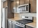 Close up of stainless steel microwave and gas range with upper and lower cabinets at 14536 Mellow Ct, Morrison, CO 80465