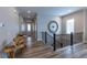Bright hallway with wood floors, decorative table, large clock and black banister leading to the upper level at 6759 Canyonpoint Rd, Castle Pines, CO 80108