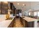 Modern kitchen featuring dark cabinetry, stainless steel appliances, a large island and white countertops and backsplash at 6759 Canyonpoint Rd, Castle Pines, CO 80108