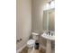 Modern powder room featuring a pedestal sink, toilet, wood floors, updated light fixtures, and dark hardware at 6759 Canyonpoint Rd, Castle Pines, CO 80108