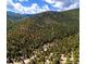 Aerial view showcasing the mountain home surrounded by lush trees, with an arrow highlighting the property's location at 1608 Beaver Brook Canyon Rd, Evergreen, CO 80439