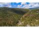 Scenic aerial view of a cozy home nestled in a lush, green mountain valley with a dirt road at 1608 Beaver Brook Canyon Rd, Evergreen, CO 80439