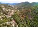 Aerial view displaying the home surrounded by lush trees in its mountain setting, indicated by an arrow at 1608 Beaver Brook Canyon Rd, Evergreen, CO 80439
