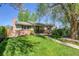 Charming single-story home featuring a brick facade, lush green lawn, and mature trees providing shade at 4781 S Grant St, Englewood, CO 80113