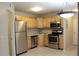 A cozy kitchen with stainless steel appliances, wooden cabinets, tile backsplash, and tile floor at 8603 E Dry Creek Rd # 211, Englewood, CO 80112