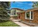 Charming home featuring a red door, brick accents, and well-maintained landscaping at 117 Sandler Dr, Lafayette, CO 80026