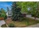 Landscaped front yard featuring mature trees, green lawn, and charming home at 117 Sandler Dr, Lafayette, CO 80026