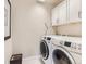 Functional laundry room with modern washer and dryer, storage cabinets, and neutral tones at 11096 Endeavor Dr, Parker, CO 80134