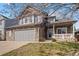 Charming two-story home with stone accents, covered porch, and manicured lawn at 8783 S Carr Way, Littleton, CO 80128