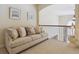Upstairs hallway featuring a comfortable sofa with decorative pillows and views to the entryway below at 4619 Mohawk Dr, Larkspur, CO 80118