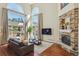 Bright living room featuring a stone fireplace, large windows, hardwood floors, and neutral-toned decor at 4619 Mohawk Dr, Larkspur, CO 80118