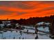 Gorgeous Colorado sunset featuring snow-covered neighborhood and pine trees at 4619 Mohawk Dr, Larkspur, CO 80118