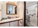 Bathroom with wood vanity, a framed mirror and glass-door shower with seat and handrails at 1002 S Miller St, Lakewood, CO 80226