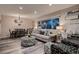 Inviting living room with a large window, patterned ottoman, gray sofa, and adjacent dining area illuminated by chandelier at 5611 W Bates Ave, Denver, CO 80227
