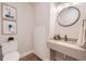 Small bathroom with a single sink, toilet, and a round mirror at 388 E Orchard Rd, Centennial, CO 80121