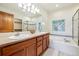Bathroom with dual sinks, soaking tub, walk-in shower, and wood cabinetry at 1024 Cottonwood Cir, Golden, CO 80401