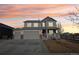 Charming two-story home featuring a three-car garage, gray siding and a welcoming front porch at sunset at 5227 Lake Port Ave, Longmont, CO 80504