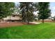 Spacious backyard with a large, green lawn, mature trees and a multi-story home at 655 Cree Cir, Boulder, CO 80303