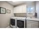 Efficient laundry room featuring modern washer and dryer, cabinet storage, and sink with window view at 3378 Shoveler Trl, Castle Rock, CO 80104