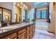 Bright bathroom with double sinks, skylight, and soaking tub with garden views at 748 Ridgeside Dr, Golden, CO 80401