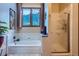 Bathroom with soaking tub, shower, and forest views from a large window at 748 Ridgeside Dr, Golden, CO 80401