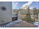 View of a wood deck with built in bench, grill, snow, and metal railing in front of trees and condos at 748 Ridgeside Dr, Golden, CO 80401