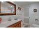 Well-lit bathroom featuring a wood vanity, framed mirror, and white door at 2309 E Floyd Pl, Englewood, CO 80113