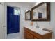 Bathroom featuring wooden vanity, ample lighting, a large mirror, and blue tiled shower at 2309 E Floyd Pl, Englewood, CO 80113