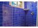 Updated shower showcasing modern blue tiles and a window for natural light at 2309 E Floyd Pl, Englewood, CO 80113