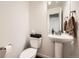 A cozy powder room with a pedestal sink, decorative mirror, and neutral finishes at 2592 Sweet Wind Ave, Castle Rock, CO 80109