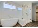 Bright bathroom featuring a glass shower, standalone tub, wood-look floors and a window at 14144 Bunny Hop Ln, Parker, CO 80134