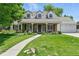 Charming stone-clad home featuring a lush green lawn and well-manicured flowerbeds at 3884 S Niagara Way, Denver, CO 80237