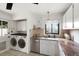 Bright laundry area with stainless steel appliances, tiled floor and granite countertops at 1411 S Beach Ct, Denver, CO 80219