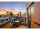 Condo balcony boasting city views with brick surround, and dark metal railing at dusk at 930 Acoma St # 420, Denver, CO 80204