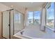 Bathroom featuring large soaking tub with a shower, plus a glass enclosed shower and large window at 17456 Quarry Way, Monument, CO 80132